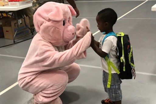Man in pig costume high fiving young boy
