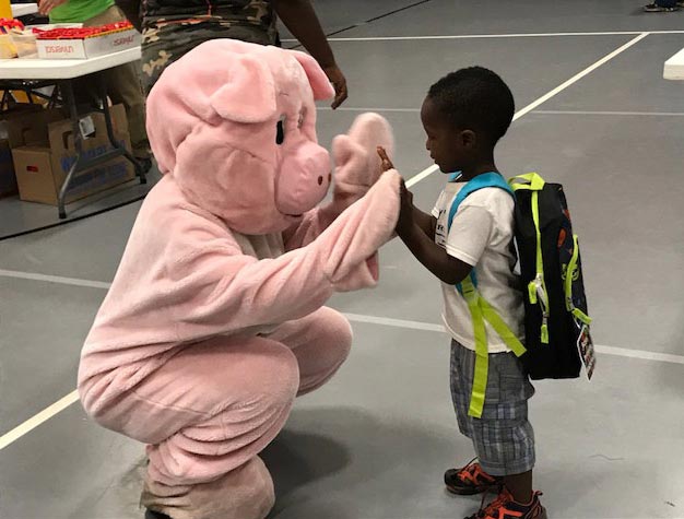 Man in pig costume high fiving young boy